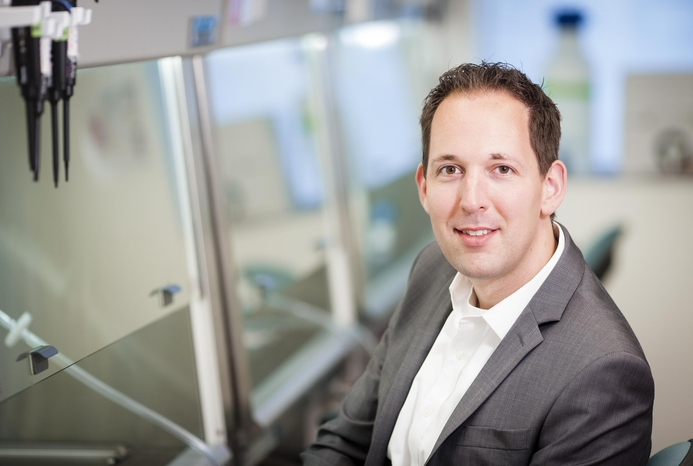 man in suit jacket sitting at lab hood