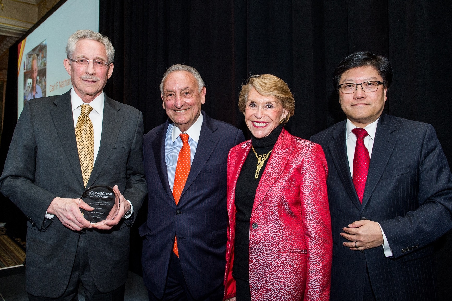 Carl Nathan accepts an Exemplary Achievement Award from Joan and Sanford Weill and Augustine Choi
