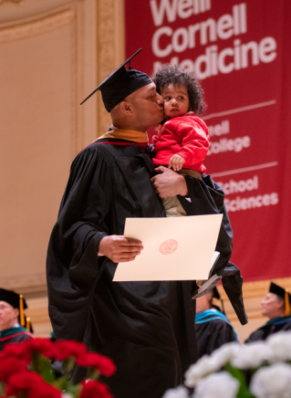 Edwin Zambrano-Acosta crosses the stage with his daughter to receive his master’s degree in healthcare policy and research.All photos taken by Amelia Panico. Click photo to view the full Commencement Flickr gallery.