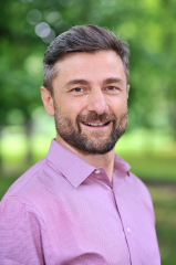 a man in a pink collared shirt posing for a picture