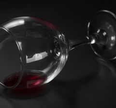 picture of a wine glass with a little red wine in it tipped onto its side